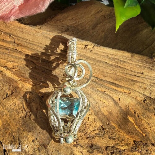 Handgefertigter Blautopas-Anhänger aus 935er Silber mit rechteckig facettiertem blauem Edelstein und geschwungener Drahtgestaltung, ca. 4,5 × 1,8 cm