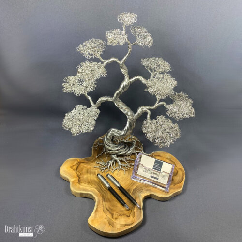 Bonsai des Morgenglanzes: ein aus silberfarbenem Aluminiumdraht hergestellter Drahtbaum, der auf einer Teakholz-Baumscheibe thront